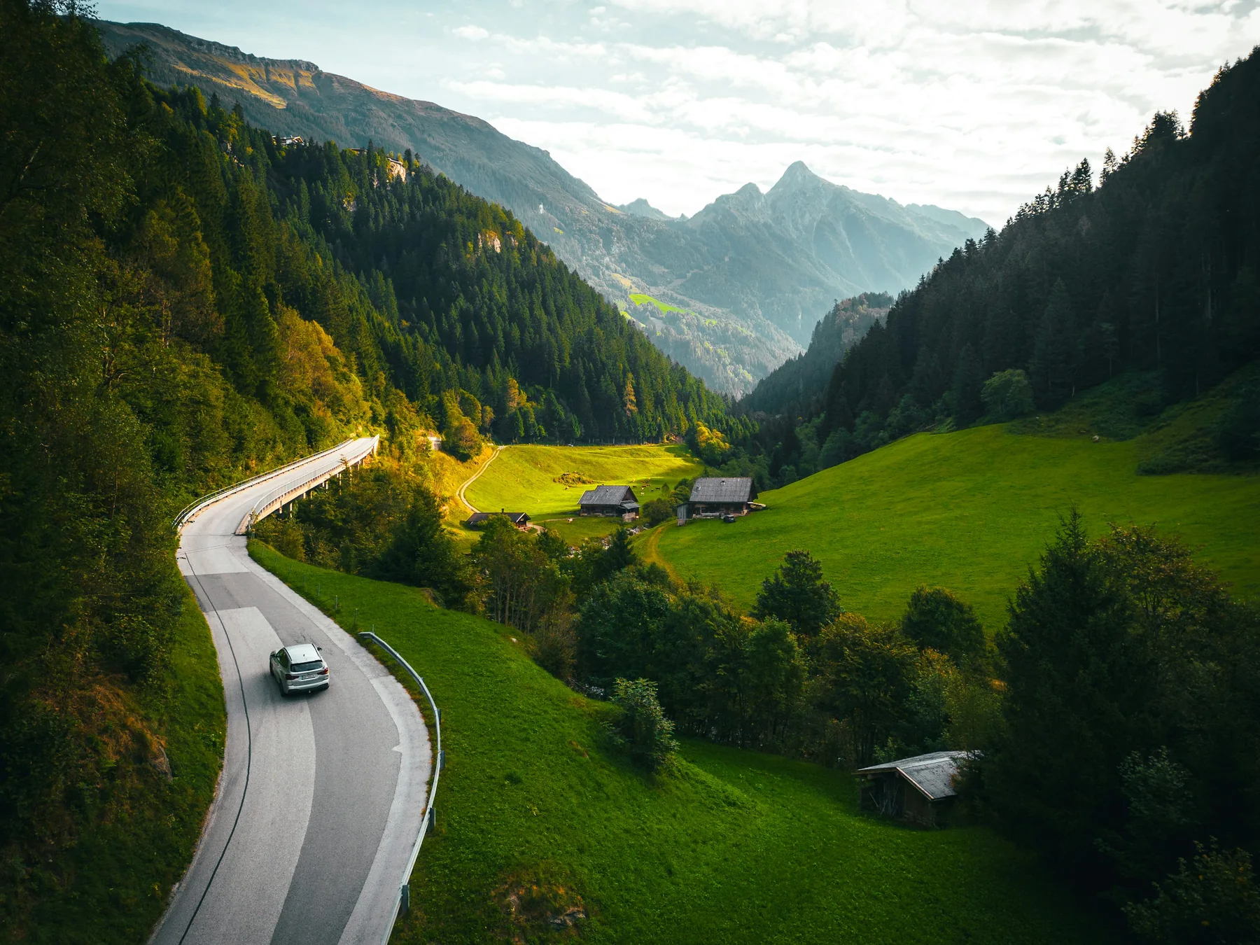 Straße schlängelt sich durch eine grüne Berglandschaft
